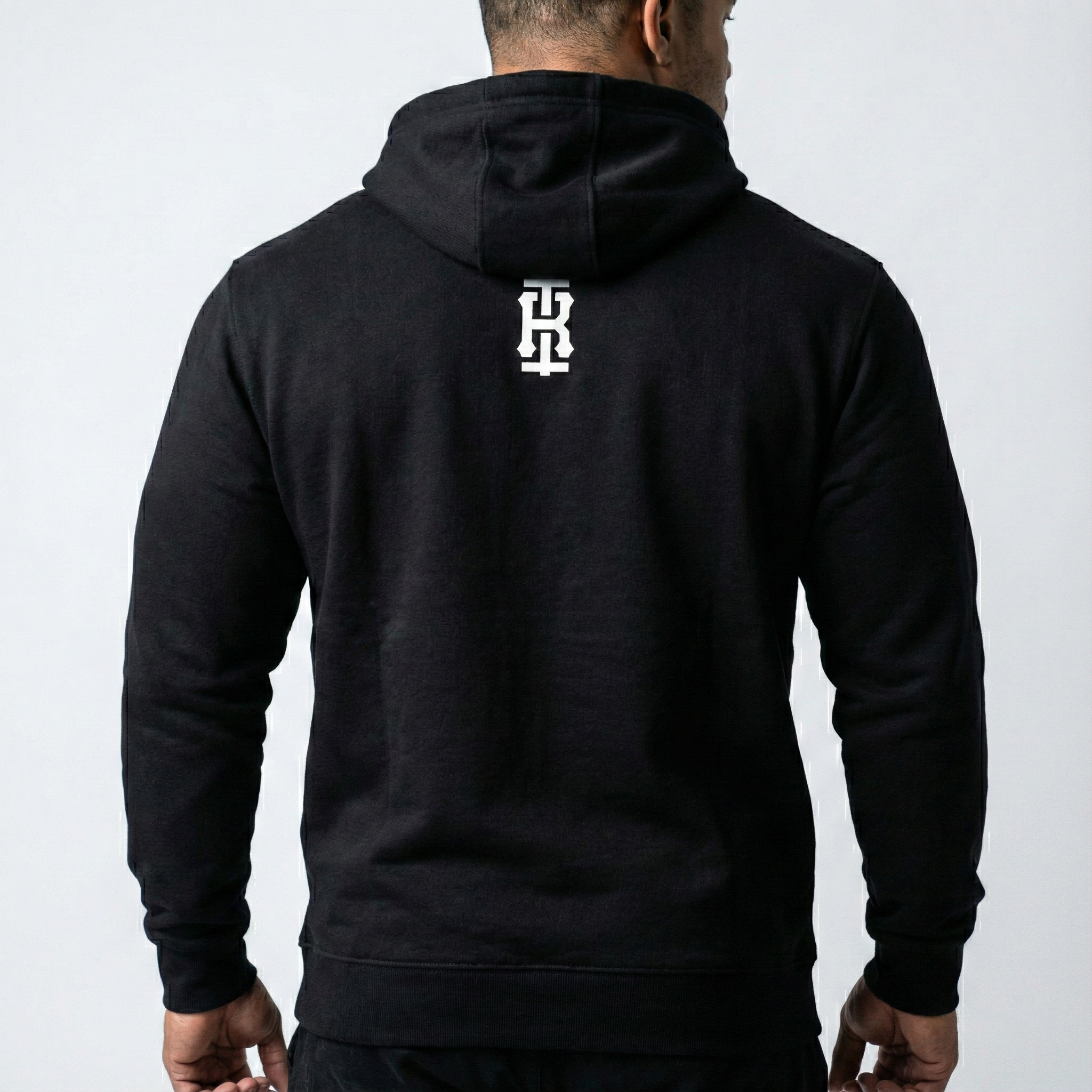 Back view of Iron Rebel black pullover hoodie for men with minimal vertical Iron Rebel logo, premium gym sweatshirt for strength athletes